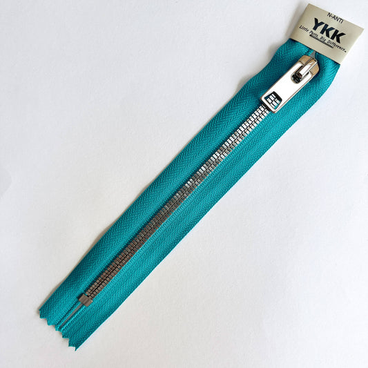 Turquoise A YKK EXCELLA® Flat closed end zip with  flat, smooth style silver metal teeth and decorative puller. 