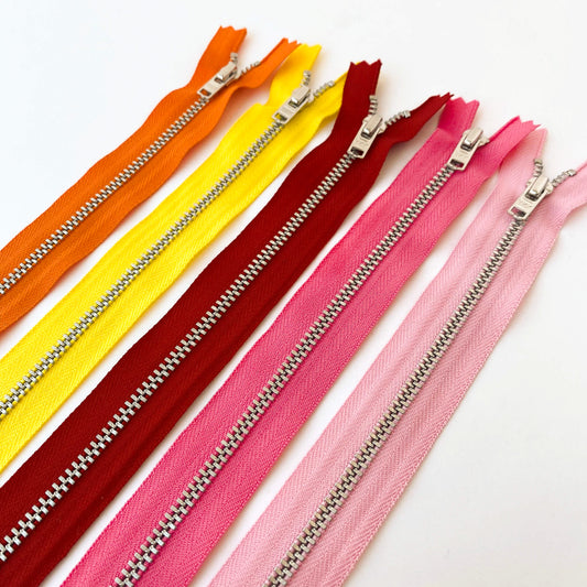 YKK  jeans zip with silver metal teeth and auto-lock puller in shades of orange, yellow, pink and red