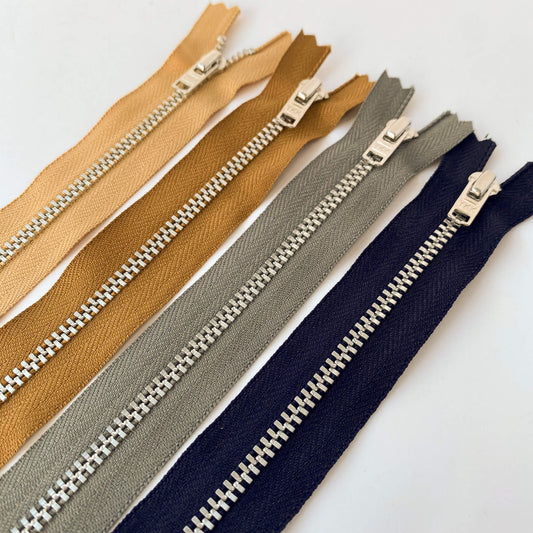 YKK  jeans zip with silver metal teeth and auto-lock puller in various shades of brown, blue and grey