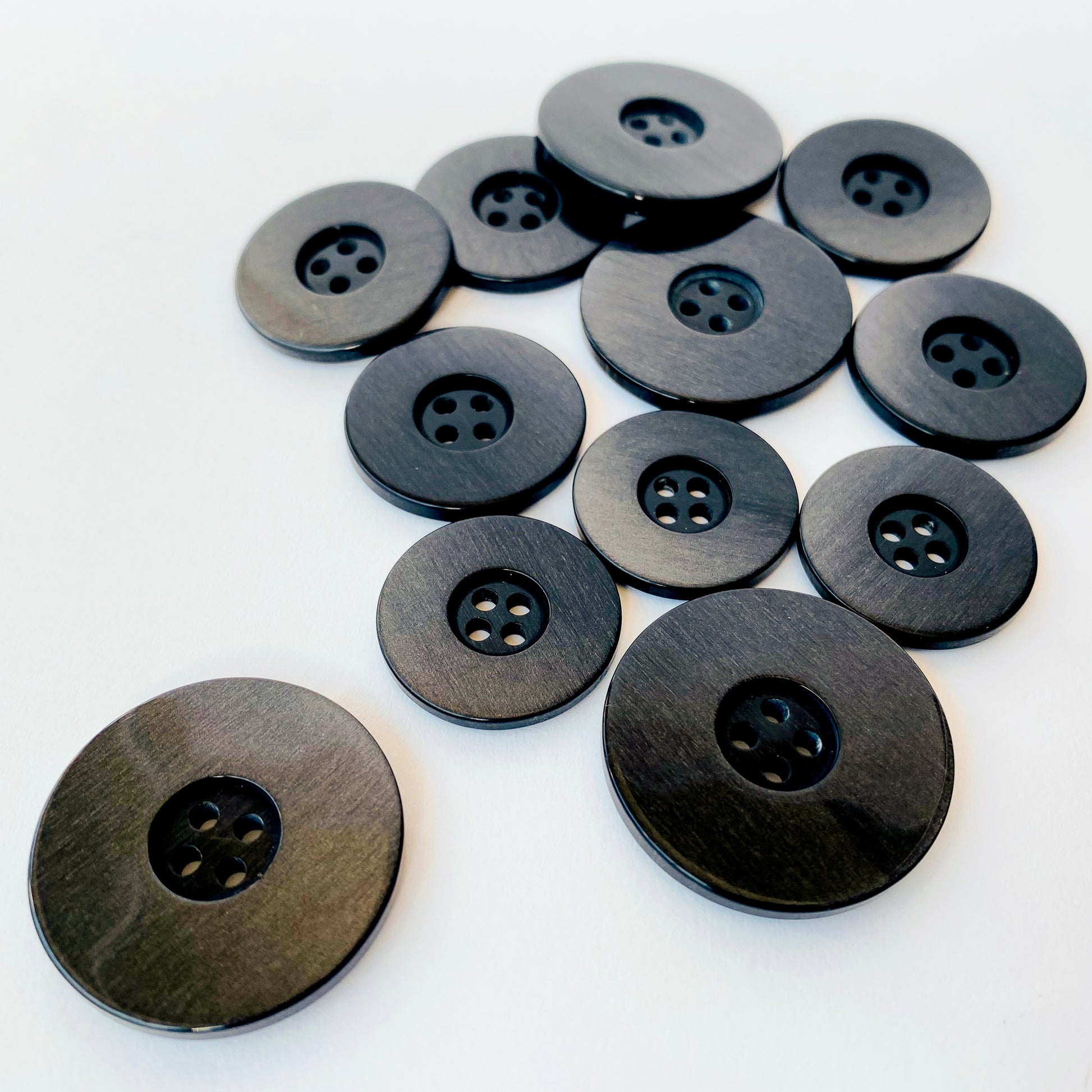 Black iridescent Buttons  Luxury, high quality hand finished iridescent suiting buttons.  Col: Black back with a pearlised luster finish to suit most dark fabrics  Sizes: 36L (23mm), 40L (26mm), 48L (31mm)  Origin: Italy / Deadstock
