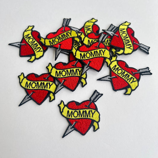 Cute patch of a red heart and arrow wrapped in a 'Mommy' banner.