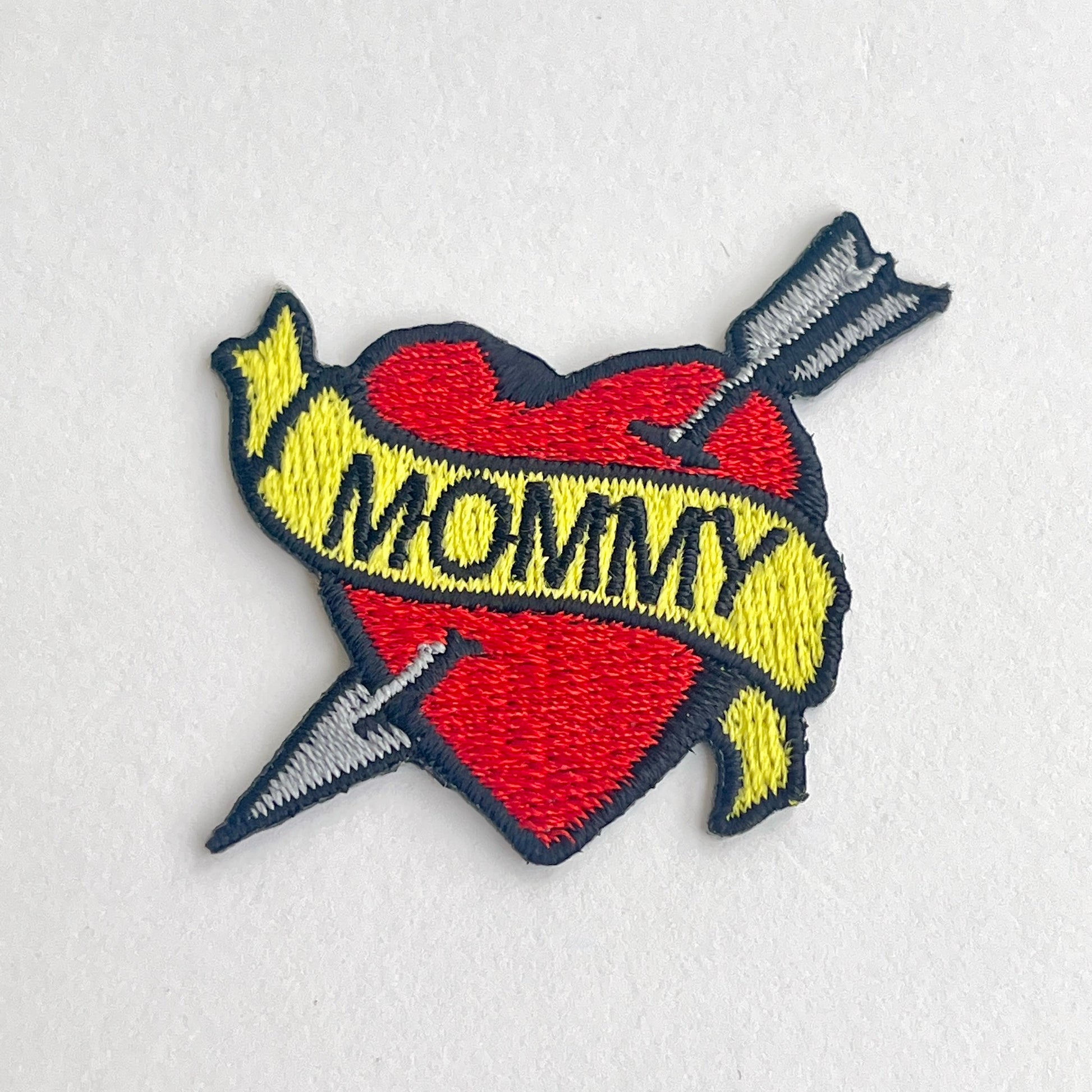 Cute patch of a red heart and arrow wrapped in a 'Mommy' banner.