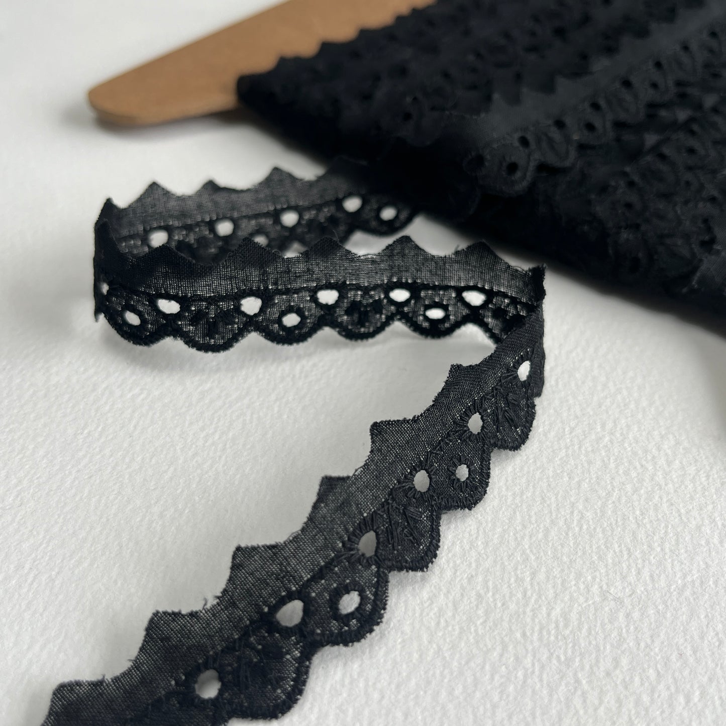 Narrow Broderie Anglaise cotton trim with scalloped edge in black. 1cm overall width / 1cm embroidered width , KLEINS HABERDASHERY. Choose our range of vintage lace, trims & sewing accoutrement rescued from a London haberdasher. Sew sustainably.