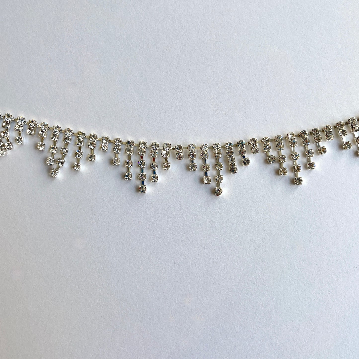 90cm length of a very sparkly rhinestone fringe trim made from premium high grade diamanté crystals set in a flexible metal chain casing. Popular for bridal wear, evening wear, crafts, jewellery and headband making.