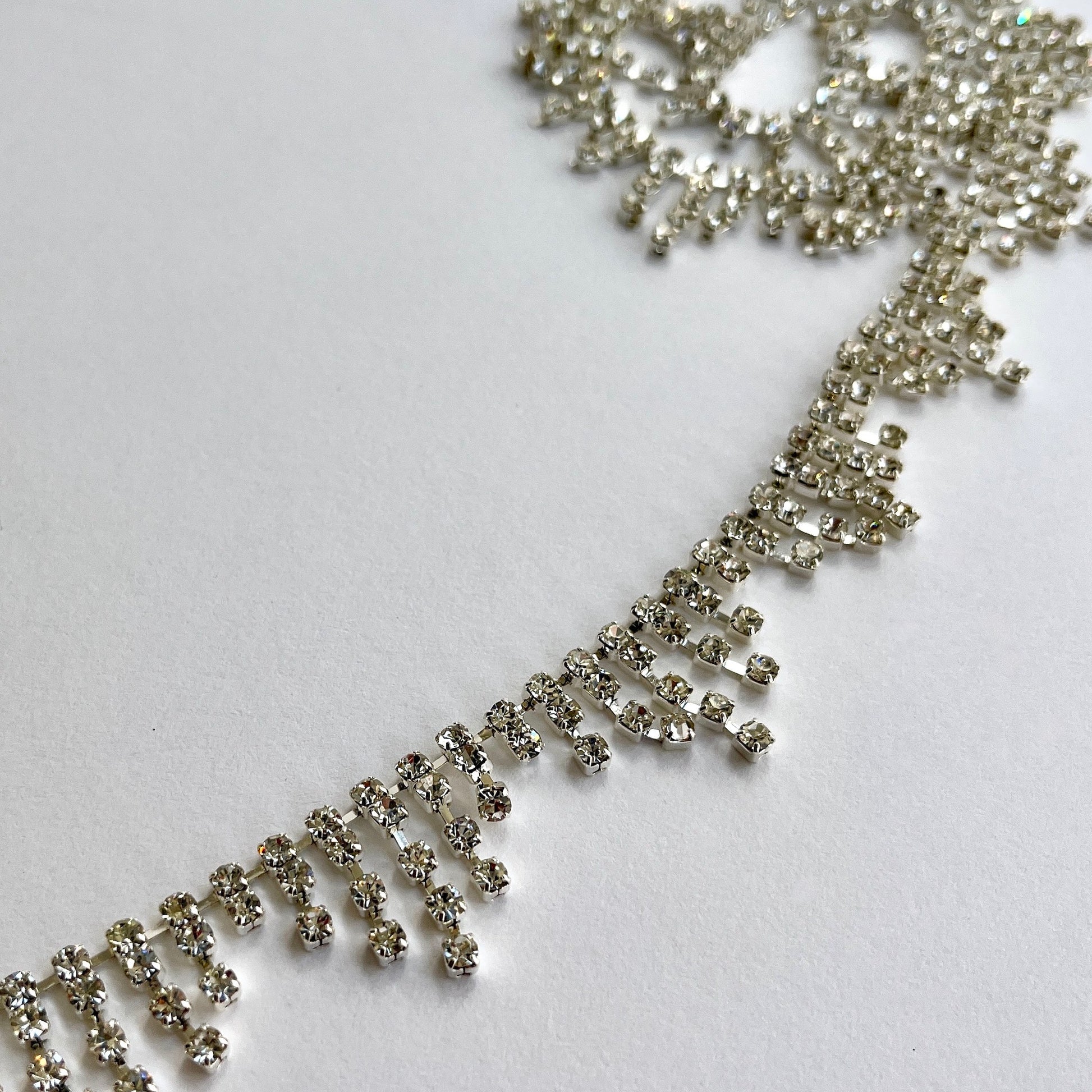 90cm length of a very sparkly rhinestone fringe trim made from premium high grade diamanté crystals set in a flexible metal chain casing. Popular for bridal wear, evening wear, crafts, jewellery and headband making.