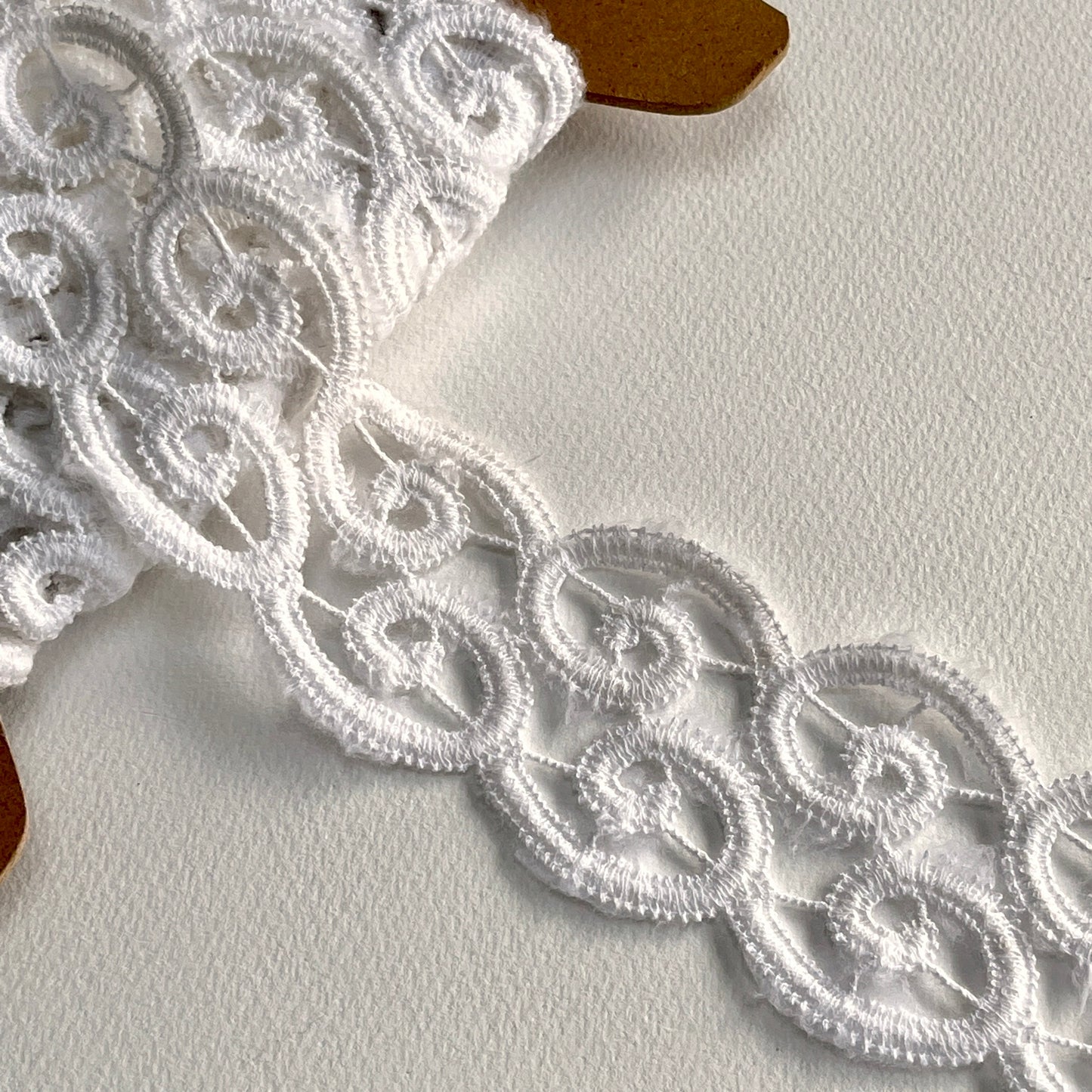 Off-white lace border trim with delicate scroll design and scalloped edge.