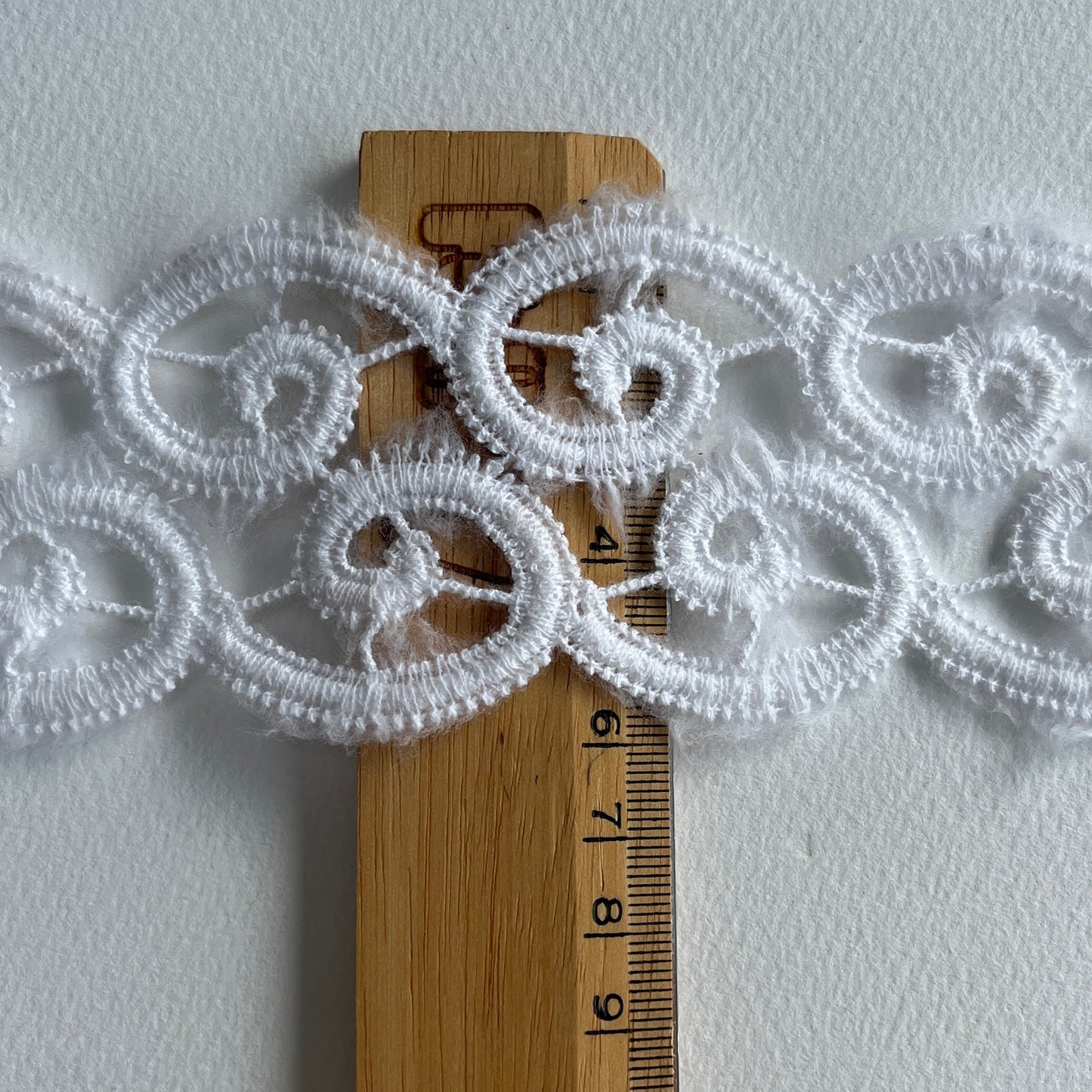 Off-white lace border trim with delicate scroll design and scalloped edge.