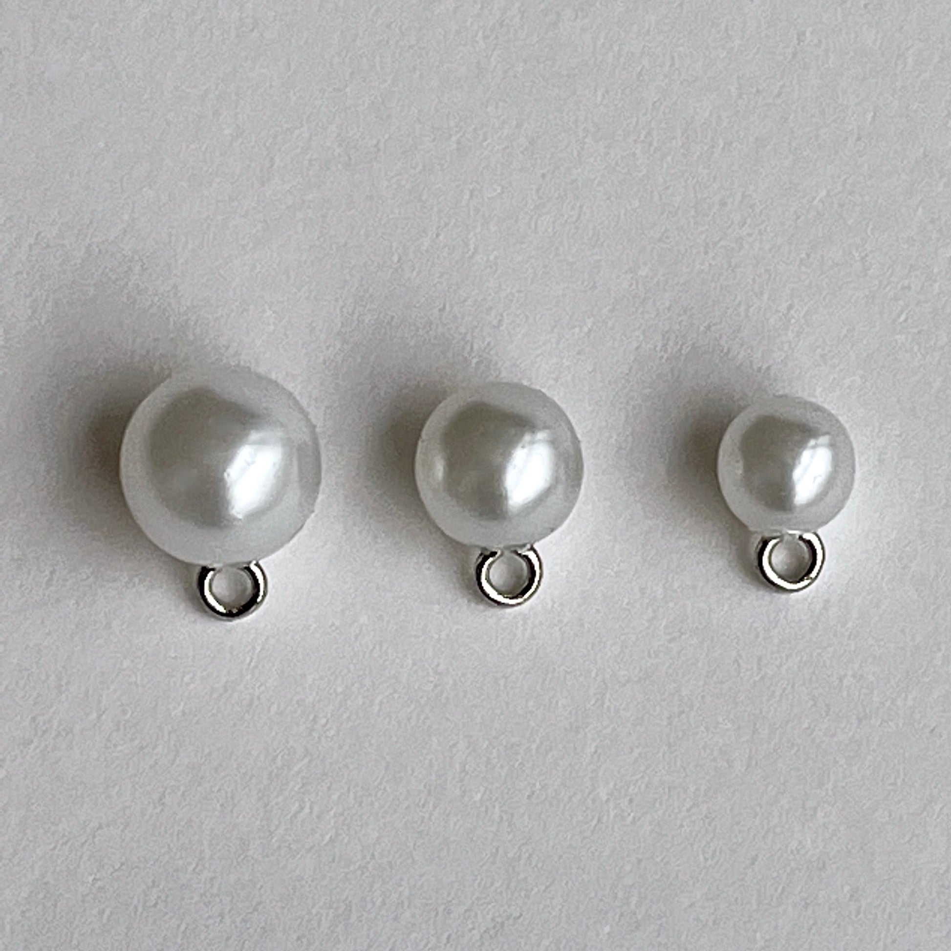 White Pearl bridal ball buttons with metal shank perfect for bridal wear, baptism and Christening gowns or even a fancy cardi! Available in either white or ivory and 3 sizes. Close up image of 3 sizes of faux pearl buttons.