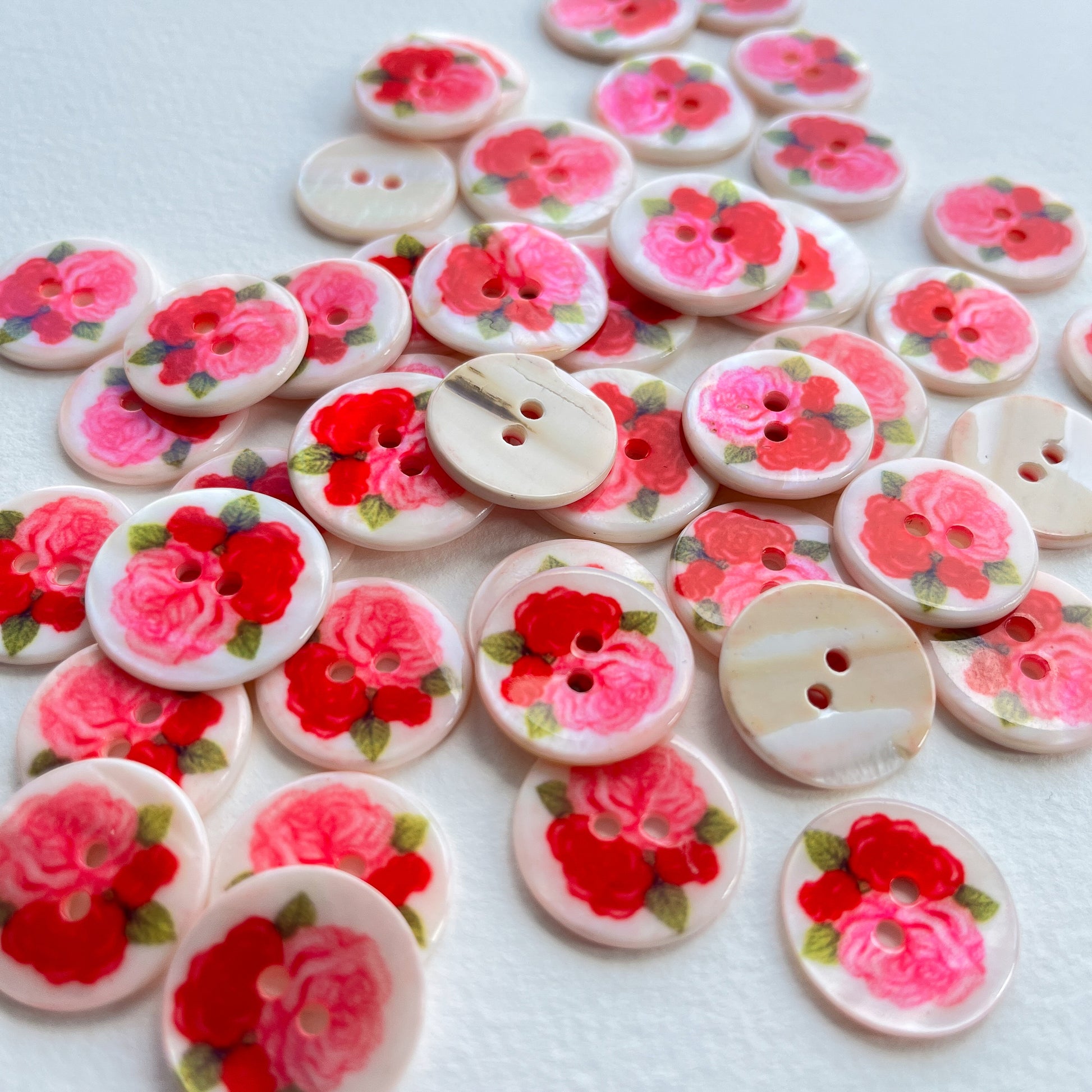 pretty lacquered Agoya shell buttons with flower design in red and pink. Deadstock haberdashery. Choose our range of vintage buttons, trims & sewing accoutrement rescued from a London haberdasher. Sew sustainably.