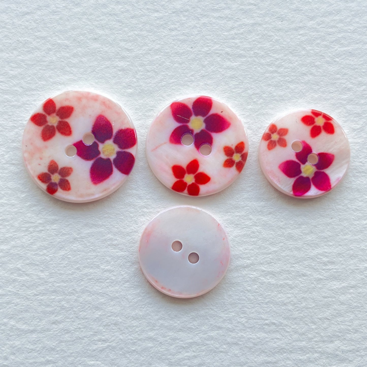 pretty lacquered Agoya shell buttons with floral design in red and pink. Deadstock haberdashery. Choose our range of vintage buttons, trims & sewing accoutrement rescued from a London haberdasher. Sew sustainably.