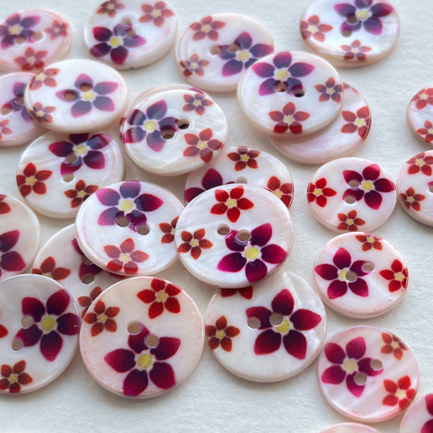 pretty lacquered Agoya shell buttons with floral design in red and pink. Deadstock haberdashery. Choose our range of vintage buttons, trims & sewing accoutrement rescued from a London haberdasher. Sew sustainably.